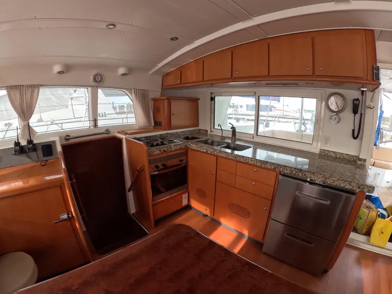 Slide: The Image of Interior of a 2006 Lagoon 440 yacht featuring a modern kitchen with wood cabinetry. - 33