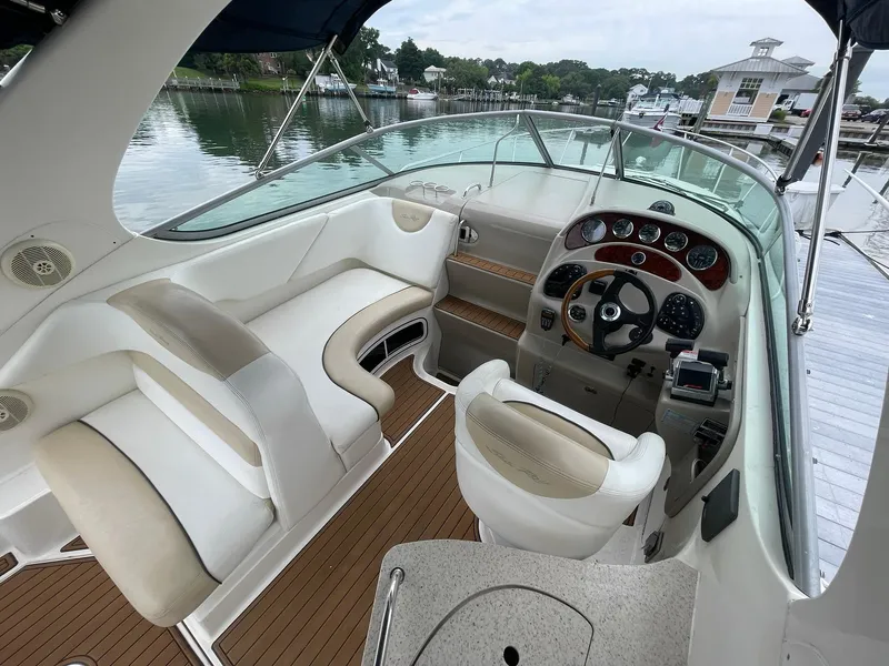 Slide: The Image of 2008 Sea Ray 280 Sundancer boat interior with helm, seating, and wood accents at a marina. - 4