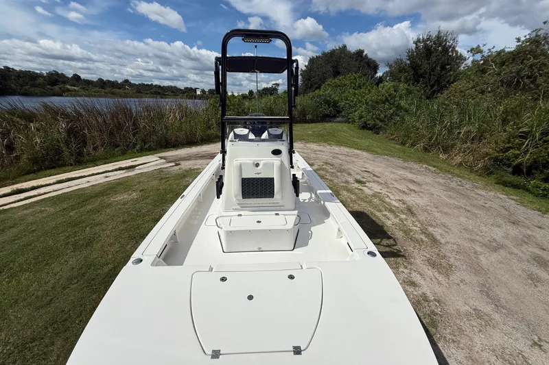 Slide: The Image of 2025 Tidewater 25 TPC Raptor boat on grassy shore, under cloudy sky. - 21