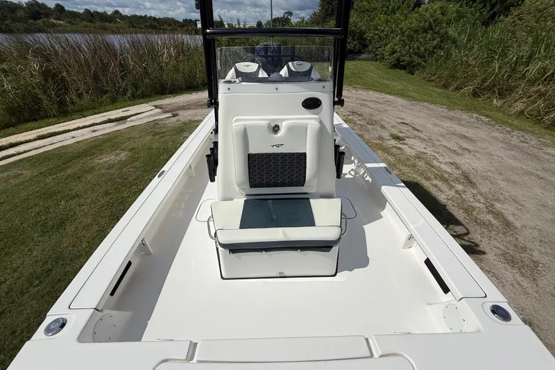 Slide: The Image of 2025 Tidewater 25 TPC Raptor boat interior with seating, parked near a grassy area. - 23