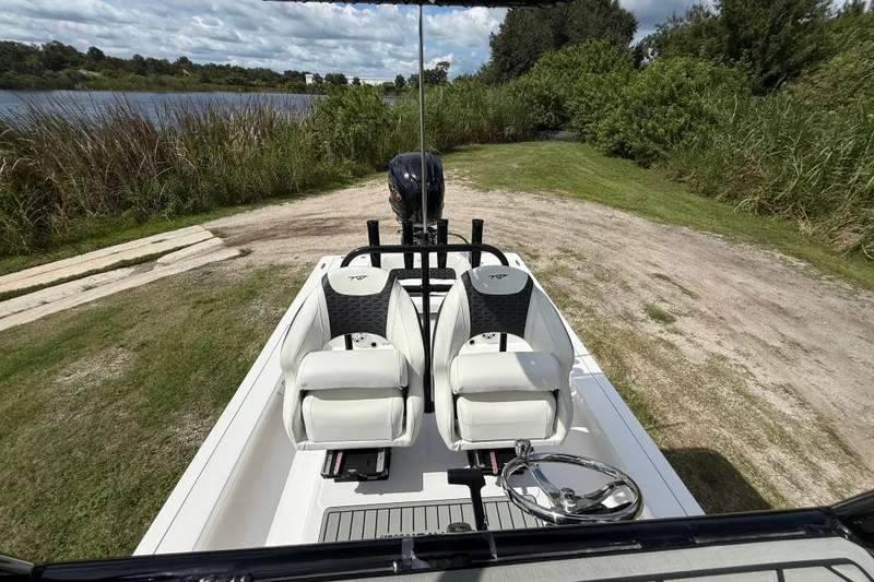 Slide: The Image of 2025 Tidewater 25 TPC Raptor boat interior with dual seats, steering wheel, and scenic lake view. - 24