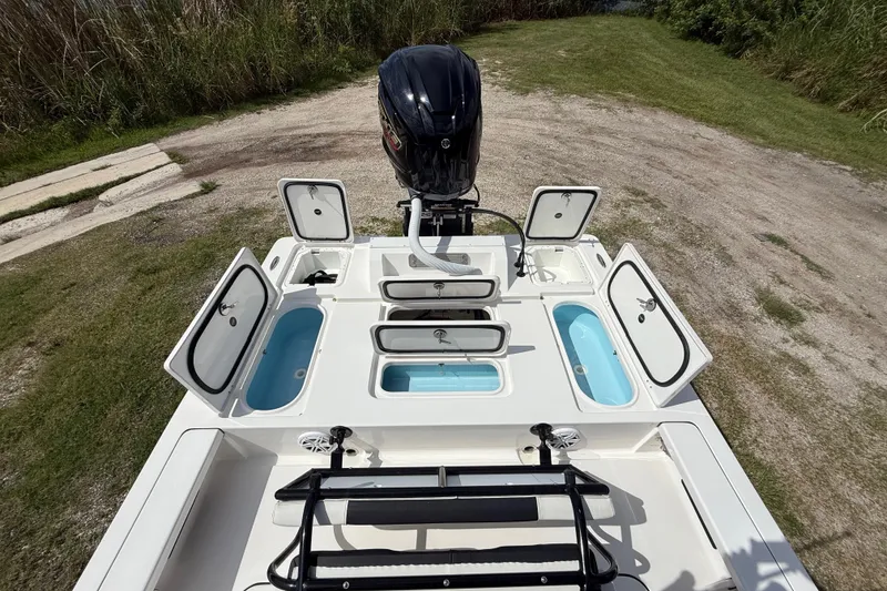 Slide: The Image of 2025 Tidewater 25 TPC Raptor boat with open storage compartments and motor, on grassy terrain. - 28