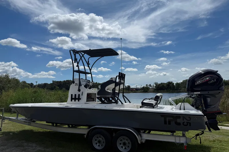 Slide: The Image of 2025 Tidewater 25 TPC Raptor boat on trailer by a lake under a cloudy sky. - 3