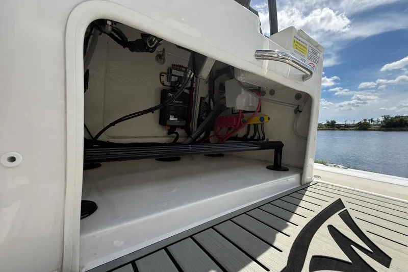 Slide: The Image of 2025 Tidewater 25 TPC Raptor boat storage compartment with wiring, near a scenic water view. - 44