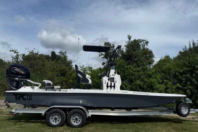 Slide: The Image of 2025 Tidewater 25 TPC Raptor boat on trailer, parked outdoors with lush greenery. - 9