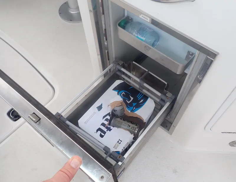 Slide: The Image of Open storage compartment on 2016 Hurricane SunDeck 2690 OB boat with magazine and water bottle. - 27