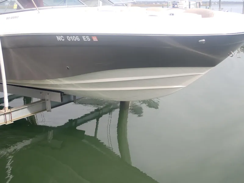 Slide: The Image of 2016 Hurricane SunDeck 2690 OB boat docked, partially lifted above calm water. - 34