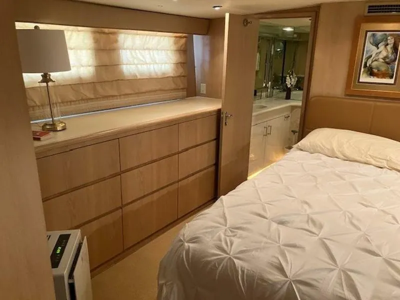 Slide: The Image of Bedroom interior of 1996 Hatteras 70 Sport Deck Motor Yacht, featuring bed, dresser, and bathroom. - 23