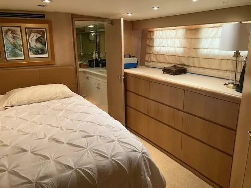 Slide: The Image of Bedroom interior of 1996 Hatteras 70 Sport Deck Motor Yacht, featuring bed, dresser, and artwork. - 24