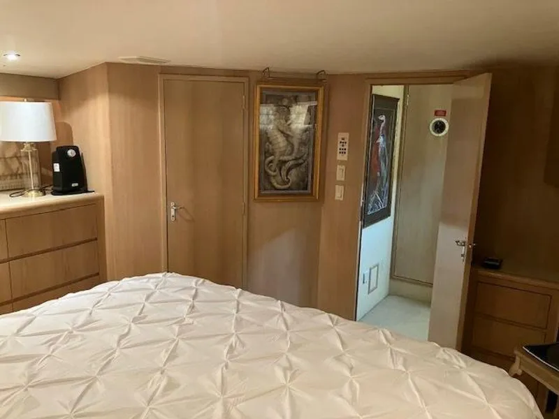 Slide: The Image of Bedroom interior of 1996 Hatteras 70 Sport Deck Motor Yacht with wood paneling and artwork. - 25