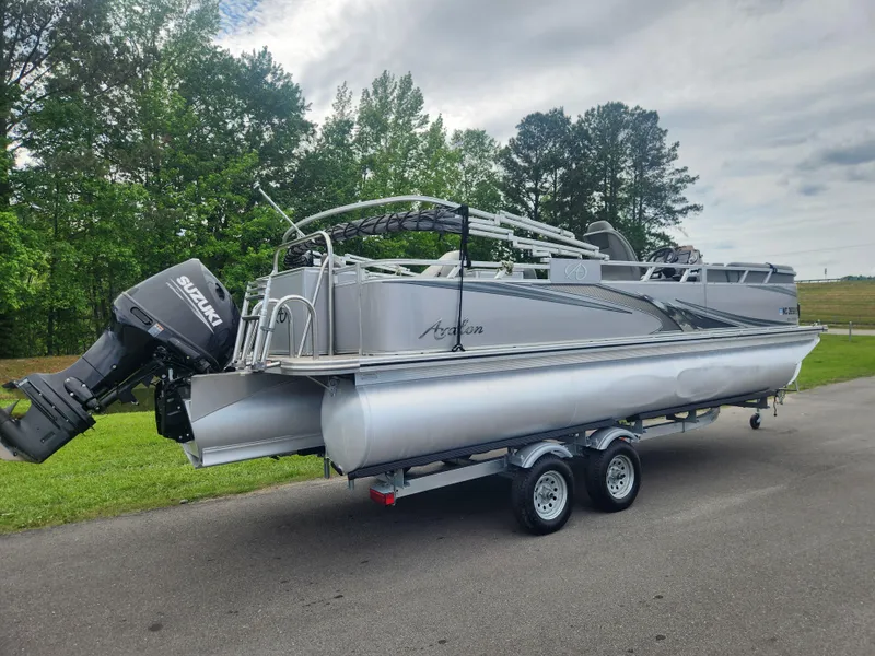 Slide: The Image of 2022 Avalon GS RF 2385 pontoon boat on trailer, parked on road with trees in background. - 2