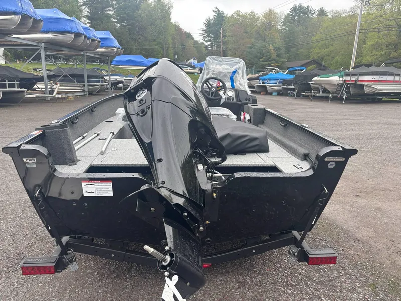 Slide: The Image of 2025 Lund 1650 Rebel XL SS boat, black exterior, parked in a marina with other boats. - 8