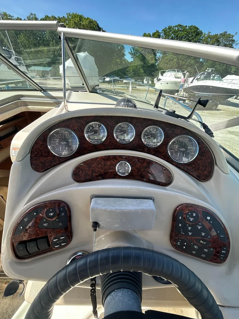 Slide: The Image of 2006 Sea Ray 280 Sundancer dashboard with gauges and controls, docked in a marina. - 4