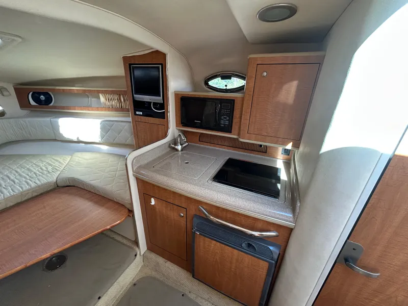 Slide: The Image of 2006 Sea Ray 280 Sundancer cabin interior with kitchenette, bed, and wood cabinetry. - 8