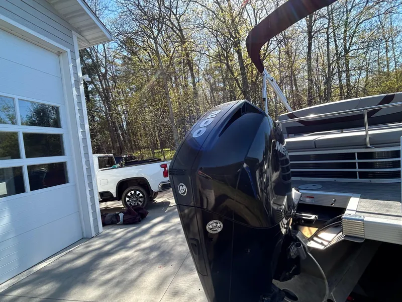 Slide: The Image of 2022 Bennington 22 SX SBST boat with outboard motor near garage and truck. - 11