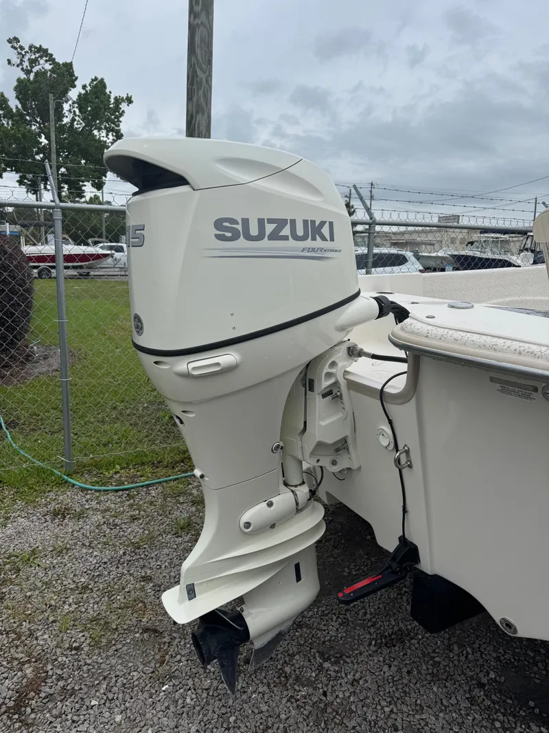 Slide: The Image of 2018 Carolina Skiff 198 DLV with Suzuki outboard motor, parked on gravel. - 2
