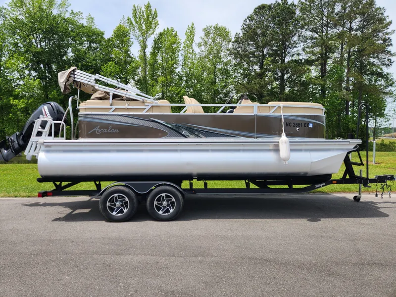 Slide: The Image of 2022 Avalon VLS 2080 QL pontoon boat on trailer, parked on road with trees in background. - 0
