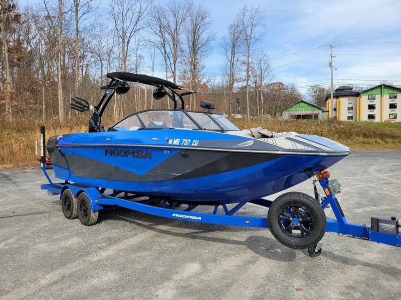 Slide: The Image of 2022 Moomba Makai boat on trailer, blue and black, parked outdoors. - 7