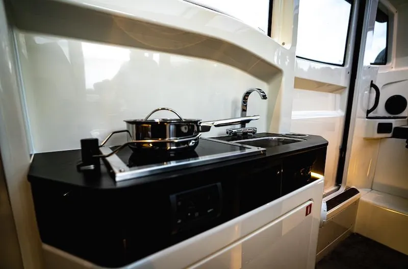 Slide: The Image of Compact kitchen area in a 2025 Navan C30, featuring a stove and sink. - 9