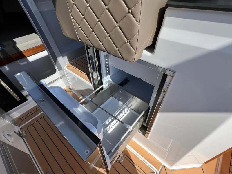 Slide: The Image of 2024 Aquador 250 HT boat interior with open storage compartment and cushioned seating. - 17