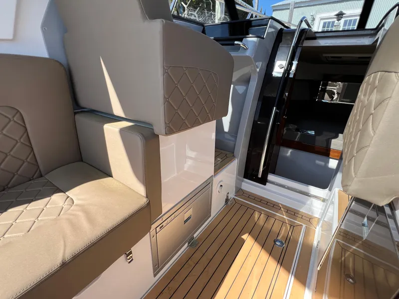 Slide: The Image of 2024 Aquador 250 HT boat interior with beige seating and wooden flooring. - 18