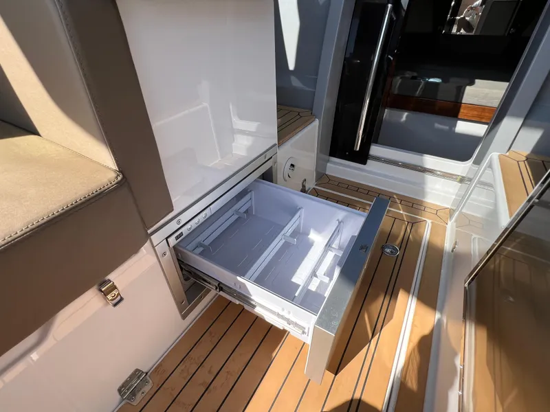 Slide: The Image of 2024 Aquador 250 HT boat interior with open storage drawer on wooden deck. - 19