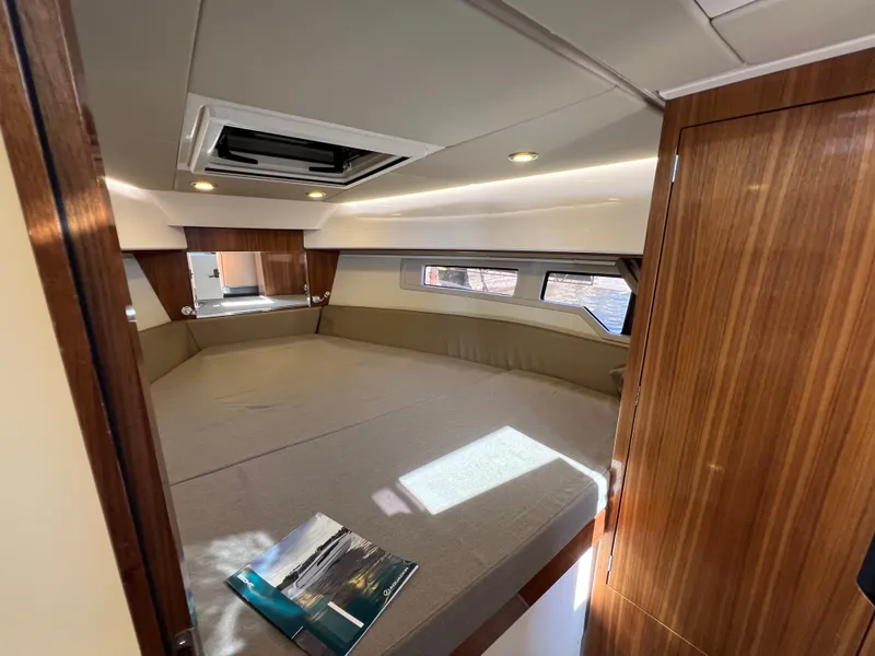 Slide: The Image of 2024 Aquador 250 HT cabin interior with wood finish and large bed. - 28