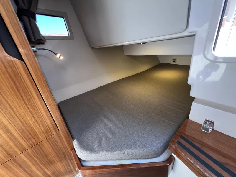 Slide: The Image of 2024 Aquador 250 HT cabin interior with cozy bed and wooden accents. - 32