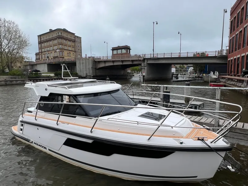 Slide: The Image of 2024 Aquador 250 HT boat docked near a bridge in an urban waterway. - 38
