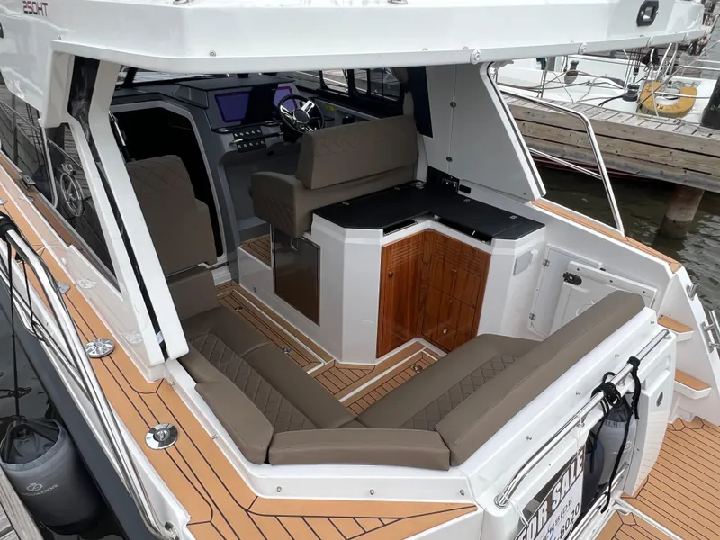 Slide: The Image of 2024 Aquador 250 HT boat interior with seating and helm, docked at marina. - 7