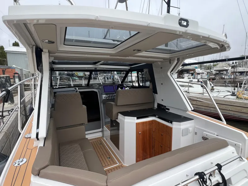 Slide: The Image of 2024 Aquador 250 HT boat interior with seating and navigation area at a marina. - 8