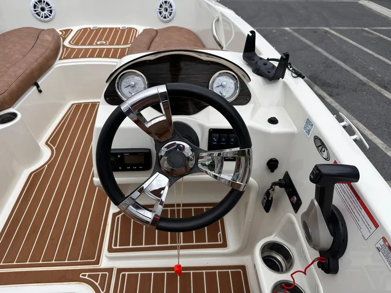 Slide: The Image of 2020 Stingray 182 SC boat dashboard with steering wheel and gauges, featuring brown and white interior. - 15