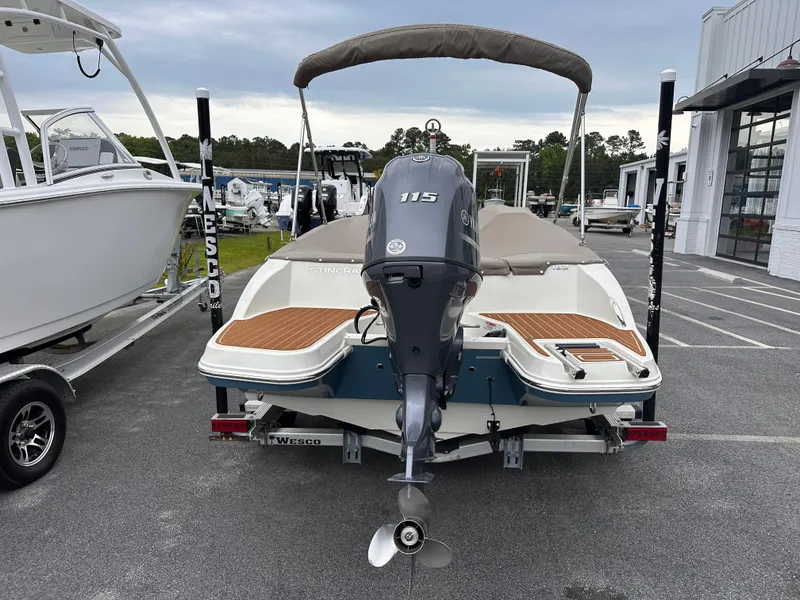 Slide: The Image of 2020 Stingray 182 SC boat with outboard motor, parked on a trailer in a marina. - 4