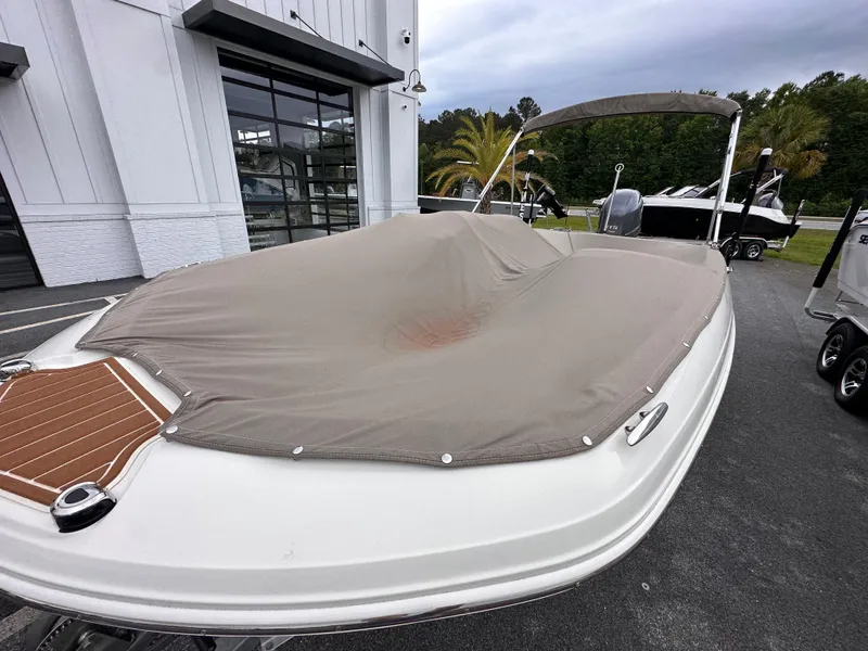 Slide: The Image of 2020 Stingray 182 SC boat with cover, parked outdoors near a modern building. - 5