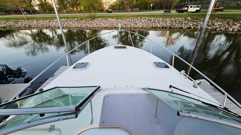 Slide: The Image of 2005 Rinker 300 Express Cruiser docked by a calm riverbank. - 16
