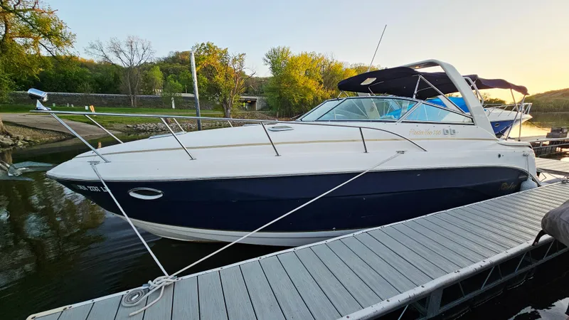 Slide: The Image of 2005 Rinker 300 Express Cruiser docked by a scenic riverside. - 3