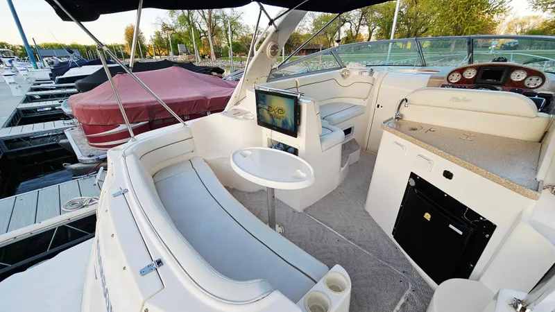 Slide: The Image of 2005 Rinker 300 Express Cruiser interior with seating, table, and dashboard at marina. - 5