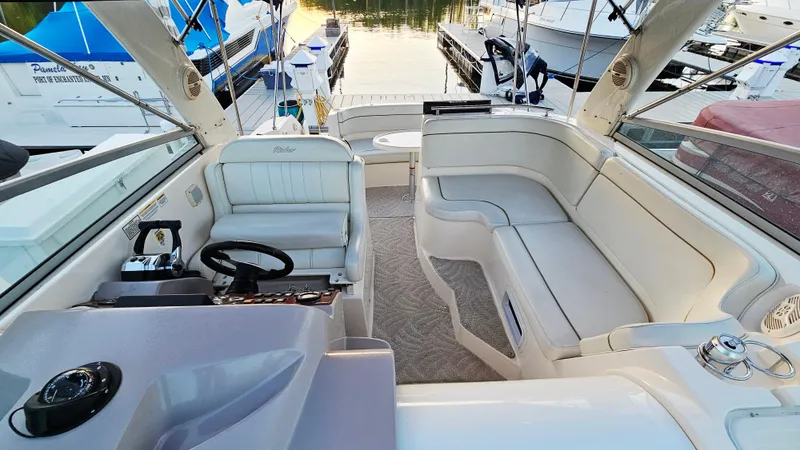 Slide: The Image of 2005 Rinker 300 Express Cruiser interior with seating and helm, docked at marina. - 7
