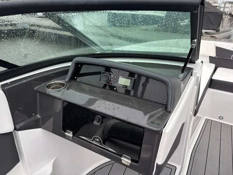 Slide: The Image of 2022 Monterey M-225 boat dashboard with modern controls and cup holder, wet from rain. - 12
