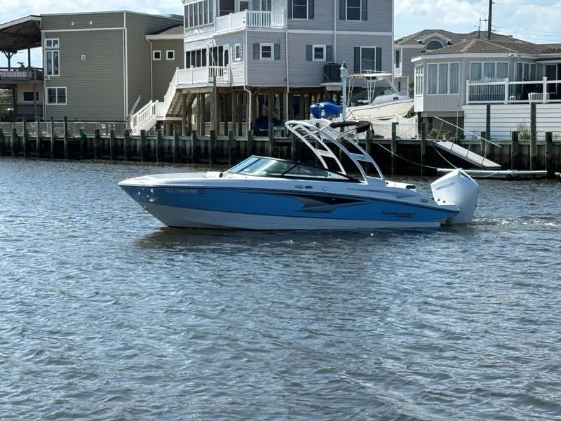Slide: The Image of 2022 Monterey M-225 boat cruising on a calm waterfront near modern houses. - 2