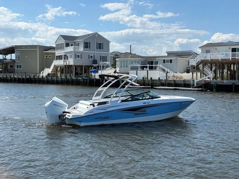 Slide: The Image of 2022 Monterey M-225 boat cruising near waterfront homes under a clear blue sky. - 6