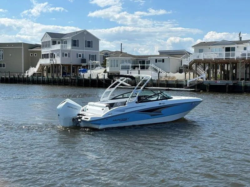 Slide: The Image of 2022 Monterey M-225 boat cruising near waterfront homes under a clear blue sky. - 8