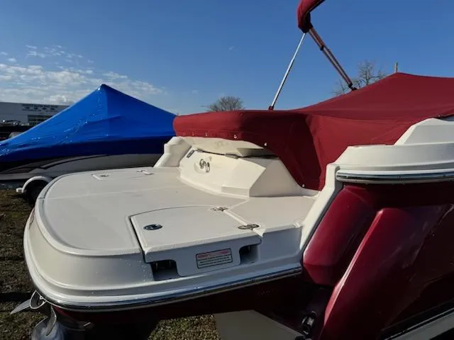 Slide: The Image of 2006 Monterey 234FS boat with red cover and swim platform, parked outdoors. - 5