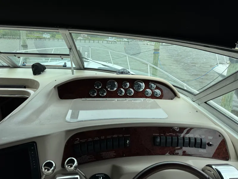 Slide: The Image of 1999 Sea Ray 330 Sundancer helm with gauges and controls, overlooking marina waters. - 13