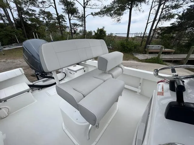 Slide: The Image of 2022 Parker 2300 SE boat with cushioned seating and outboard motor, set in a wooded area. - 10