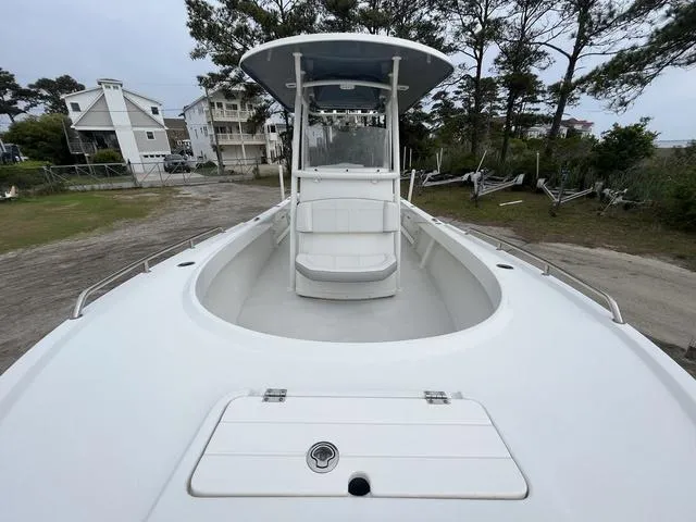 Slide: The Image of 2022 Parker 2300 SE boat with T-top, docked near coastal homes and trees. - 7