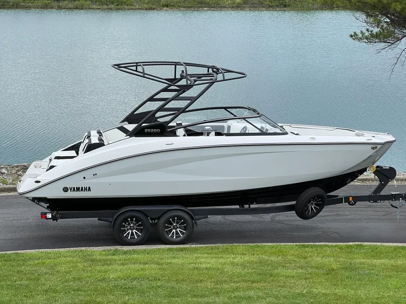 Slide: The Image of 2025 Yamaha Boats 252SD on trailer by a lake, showcasing sleek design and modern features. - 1