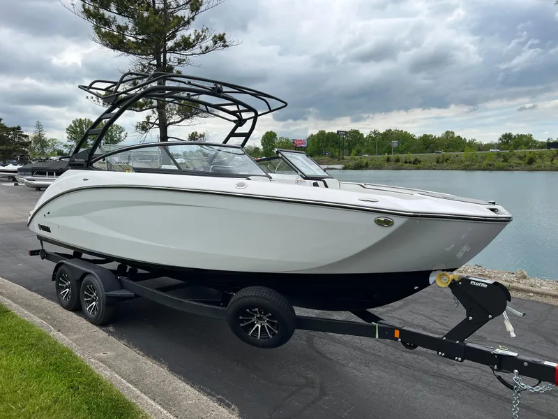Slide: The Image of 2025 Yamaha Boats 252SD on trailer by a lake, under cloudy sky. - 2