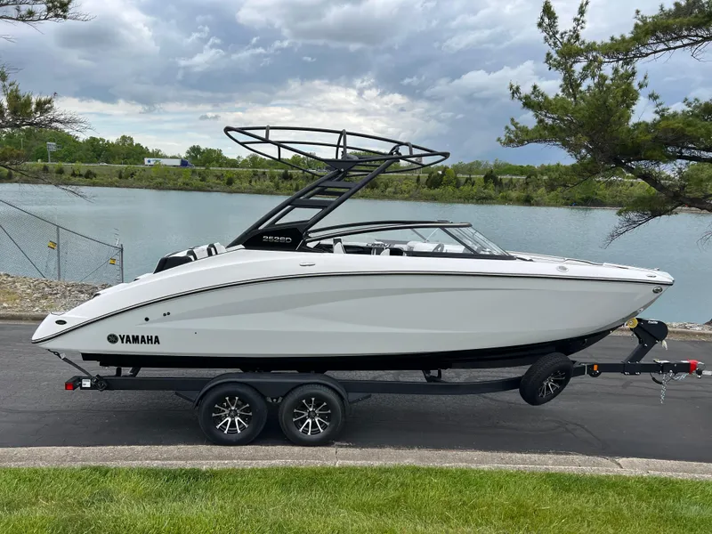 Slide: The Image of 2025 Yamaha Boats 252SD on trailer by a lake, under cloudy sky. - 3
