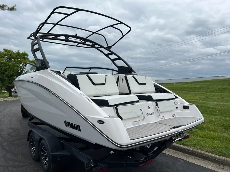 Slide: The Image of 2025 Yamaha Boats 252SD on trailer, sleek design, white exterior, black accents, overcast sky. - 6